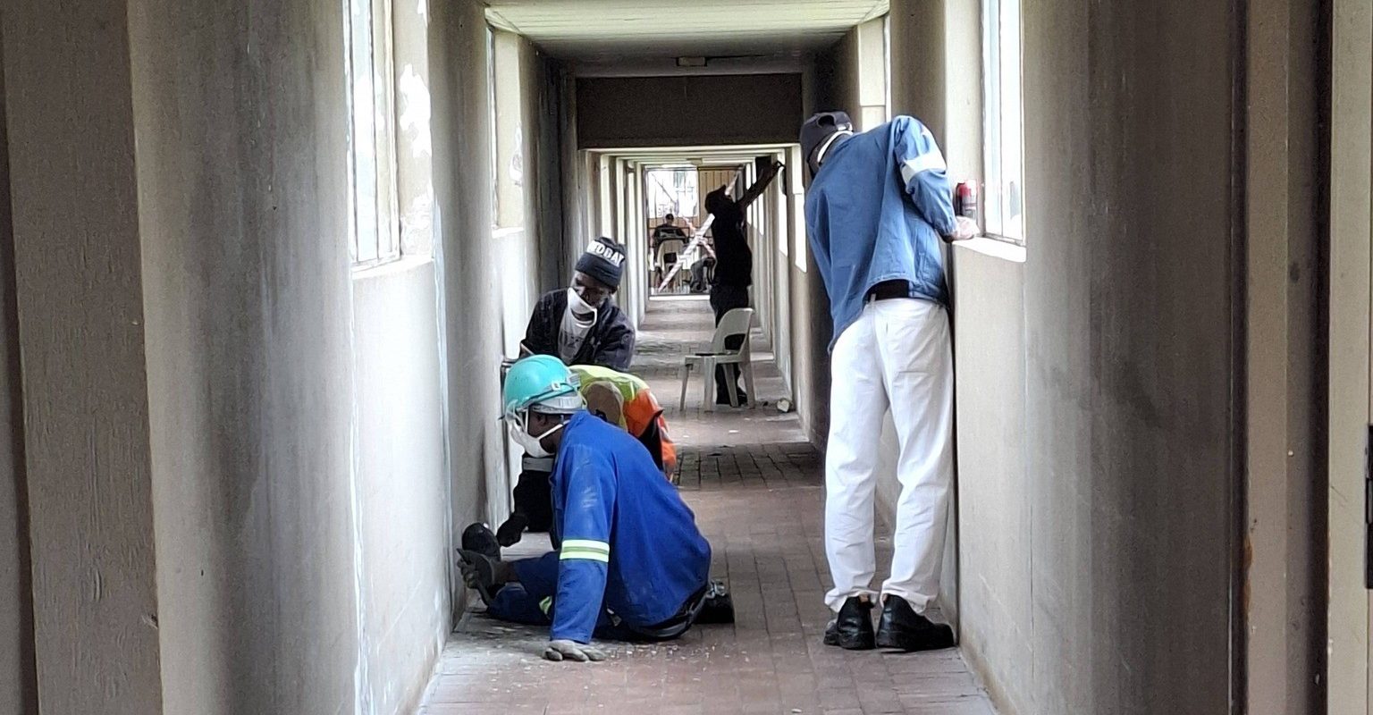 Workers busy in the hallway of Vita Nova stripping walls for painting