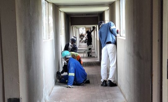 Workers busy in the hallway of Vita Nova stripping walls for painting
