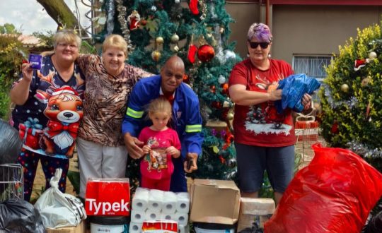 Workers of Vita Nova standing in front of Christmas tree with donations from Pinegrove Primary